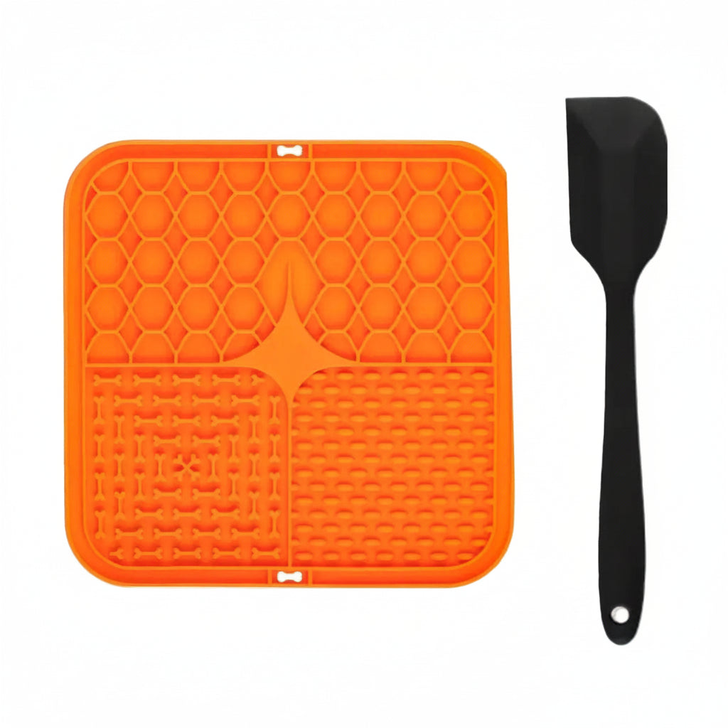 Orange silicone licking mat with black scraper on a white background
