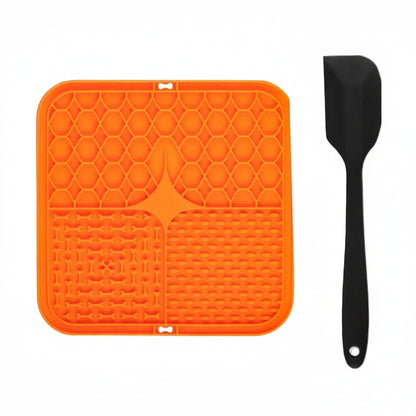 Orange silicone licking mat with black scraper on a white background